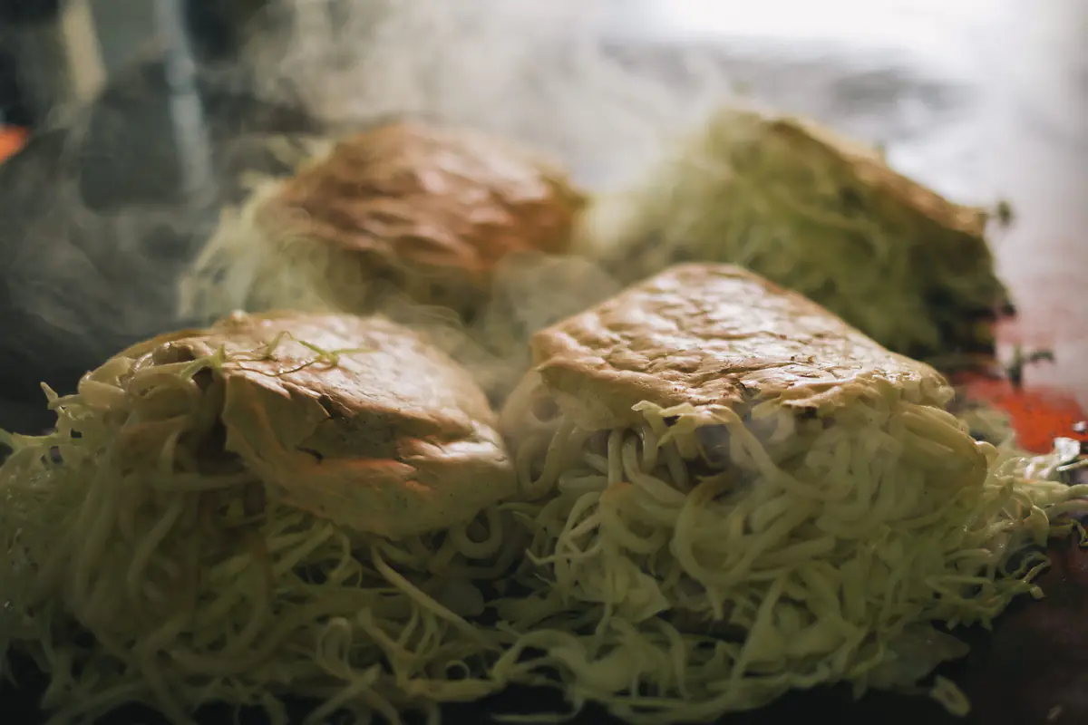 湯気の立つ鉄板の上で蒸し焼きにされるキャベツ