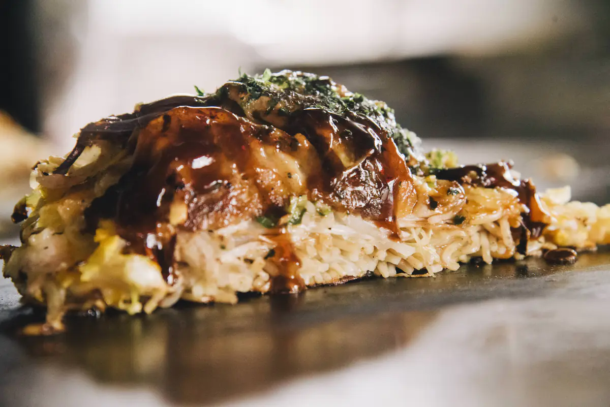 鉄板の上で焼きあがった、ソースの照りが光るお好み焼き