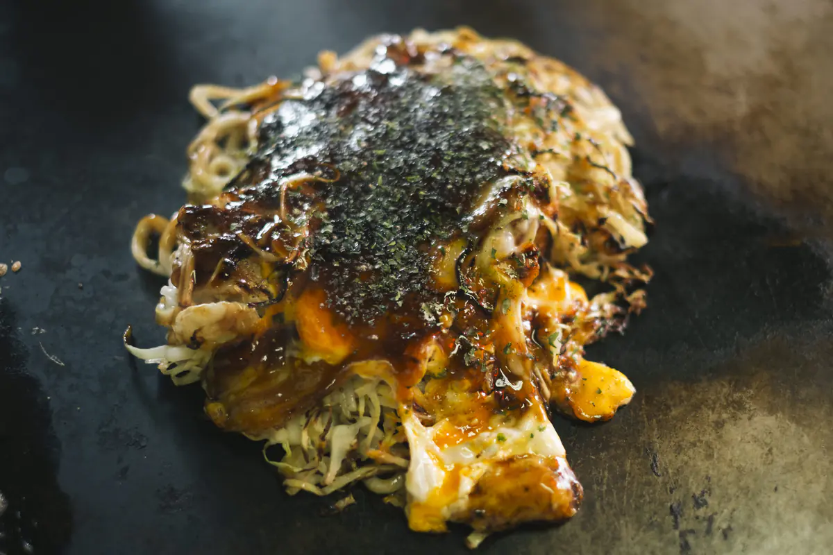 半熟卵とソースが絡む焼きたてのお好み焼き